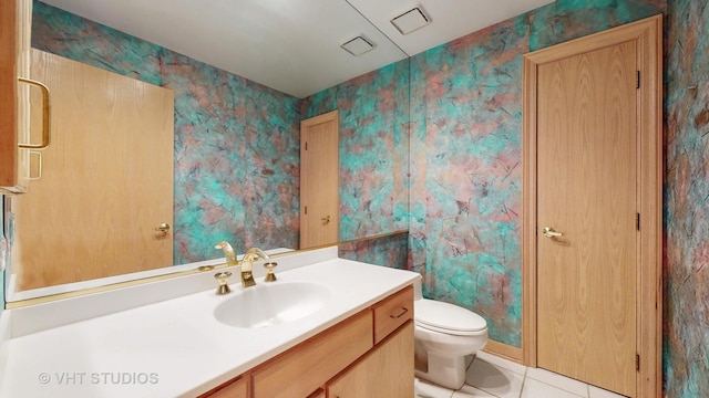 bathroom with toilet, vanity, and tile patterned floors