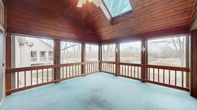 unfurnished sunroom with lofted ceiling with skylight, ceiling fan, a healthy amount of sunlight, and wood ceiling