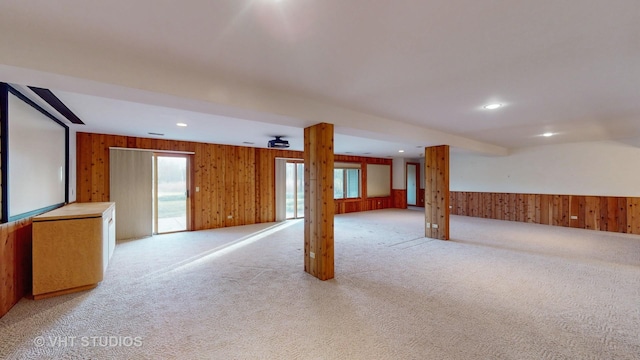 unfurnished room featuring light carpet, ceiling fan, and wood walls