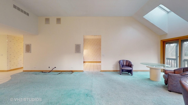 unfurnished living room with vaulted ceiling with skylight and carpet flooring