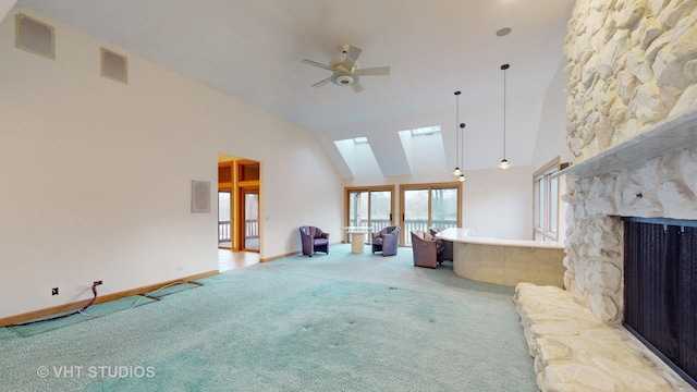 unfurnished living room with carpet flooring, a skylight, ceiling fan, high vaulted ceiling, and a fireplace