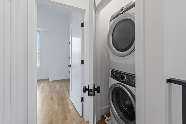 laundry room featuring light hardwood / wood-style floors and stacked washing maching and dryer