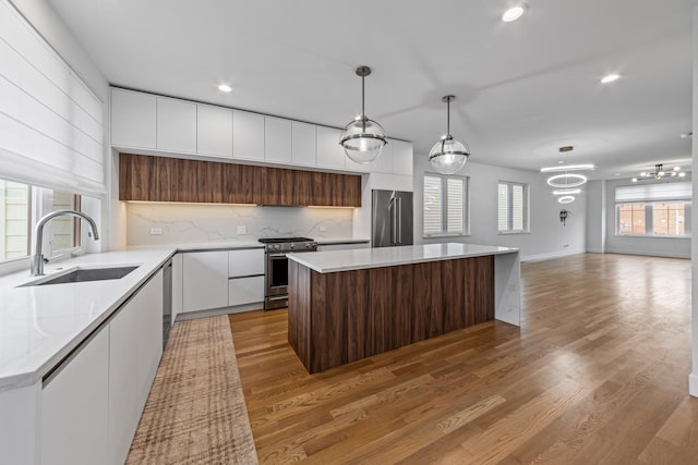 kitchen featuring pendant lighting, appliances with stainless steel finishes, sink, and a kitchen island