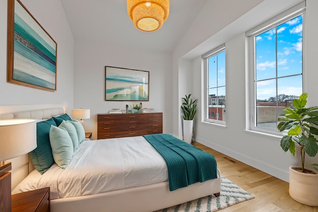 bedroom with lofted ceiling and light wood-type flooring