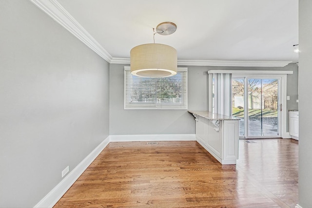 unfurnished dining area with wood-type flooring and crown molding