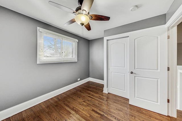 unfurnished bedroom with ceiling fan, a closet, and dark hardwood / wood-style floors