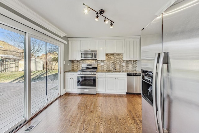 kitchen featuring appliances with stainless steel finishes, light hardwood / wood-style floors, white cabinetry, and crown molding