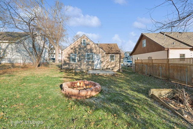 back of property featuring a fire pit and a yard