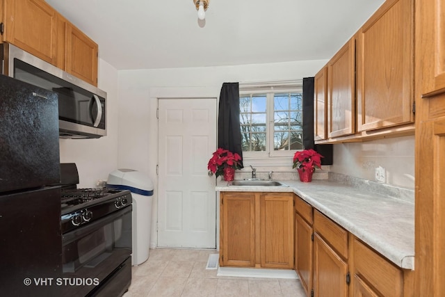 kitchen featuring sink, light tile patterned flooring, and black appliances