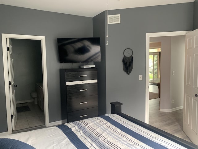 bedroom featuring ensuite bath and light wood-type flooring