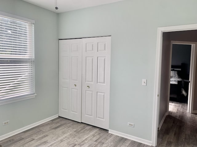 unfurnished bedroom with a closet and light wood-type flooring