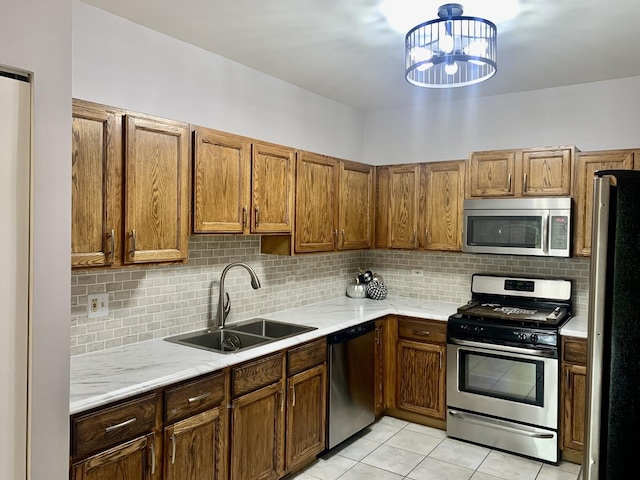 kitchen featuring backsplash, sink, a notable chandelier, light tile patterned flooring, and stainless steel appliances