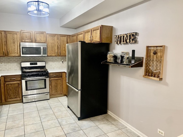 kitchen with stainless steel appliances, a notable chandelier, backsplash, pendant lighting, and light tile patterned floors