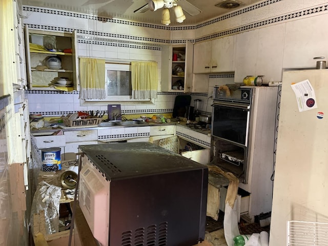 kitchen featuring black oven, ceiling fan, and sink