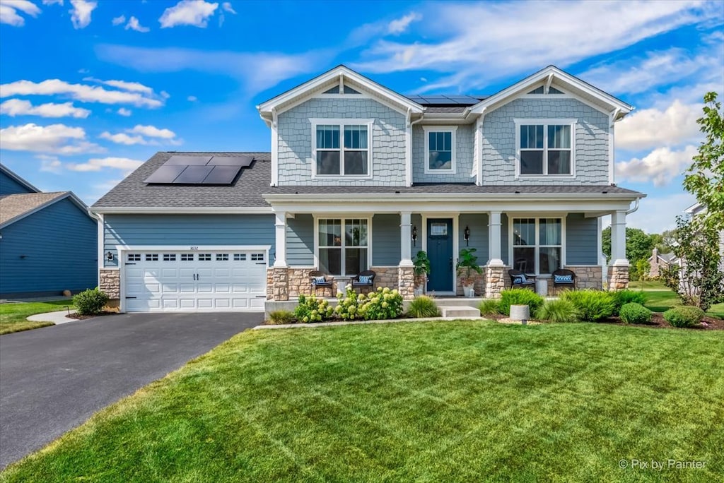 craftsman-style home featuring solar panels, a garage, covered porch, and a front yard