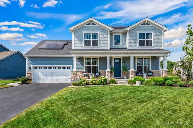 craftsman-style home featuring solar panels, a garage, covered porch, and a front yard