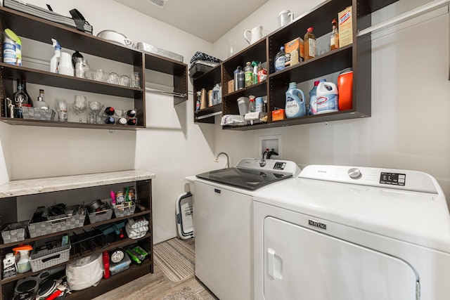 clothes washing area with light wood-type flooring and washing machine and dryer