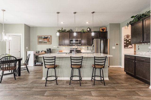 kitchen with dark brown cabinets, dark hardwood / wood-style flooring, stainless steel appliances, and decorative light fixtures