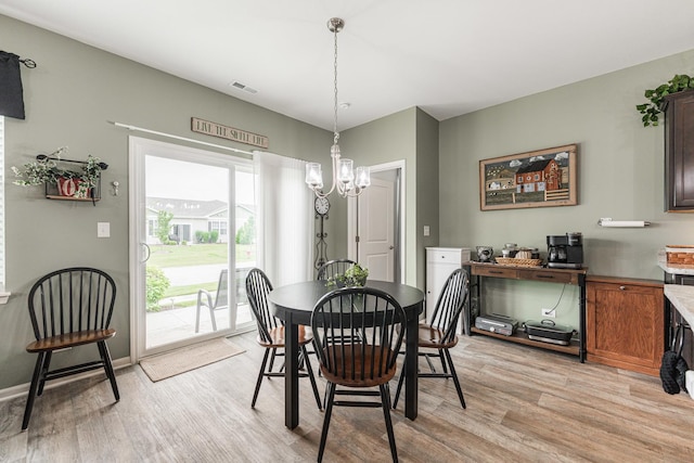 dining room with light hardwood / wood-style floors and a notable chandelier