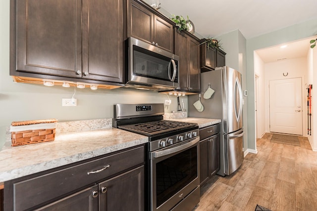 kitchen with dark brown cabinets, light hardwood / wood-style floors, and appliances with stainless steel finishes