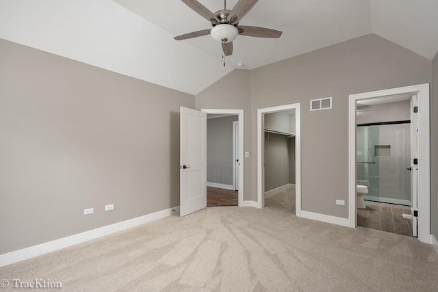 unfurnished bedroom featuring ceiling fan, a walk in closet, light carpet, and vaulted ceiling