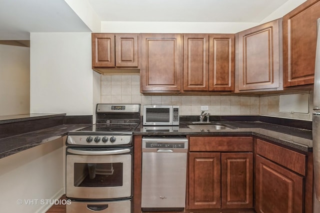 kitchen with appliances with stainless steel finishes, sink, backsplash, and dark stone counters