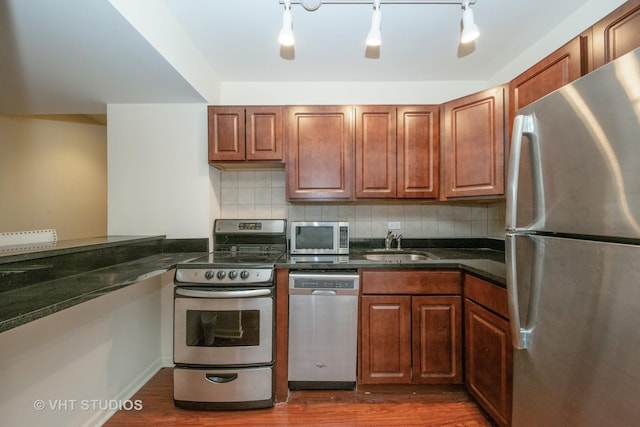 kitchen with sink, decorative backsplash, dark wood-type flooring, and appliances with stainless steel finishes