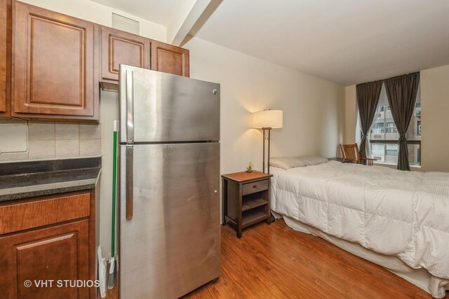 bedroom featuring hardwood / wood-style flooring and stainless steel fridge