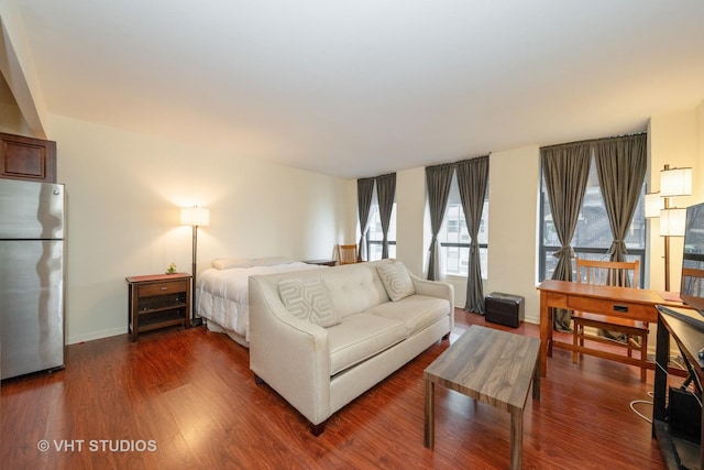 bedroom featuring stainless steel fridge and dark hardwood / wood-style flooring