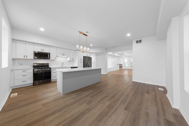 kitchen with white cabinetry, wood-type flooring, hanging light fixtures, and appliances with stainless steel finishes