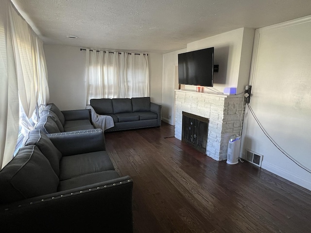 living room with a fireplace, dark hardwood / wood-style floors, and a textured ceiling