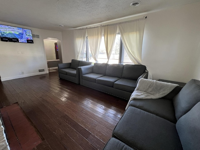 living room with a textured ceiling and dark hardwood / wood-style floors