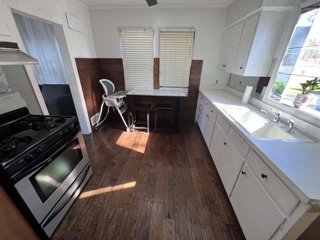 kitchen featuring gas stove, range hood, white cabinetry, and sink