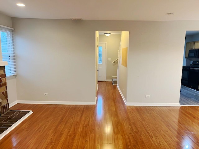 unfurnished living room featuring light wood-type flooring and a tiled fireplace