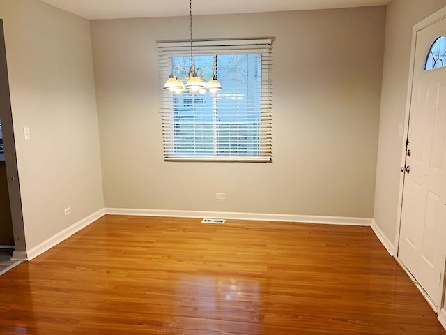 unfurnished dining area featuring hardwood / wood-style flooring and an inviting chandelier