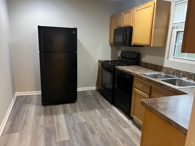 kitchen with black appliances, light hardwood / wood-style floors, sink, and a wealth of natural light