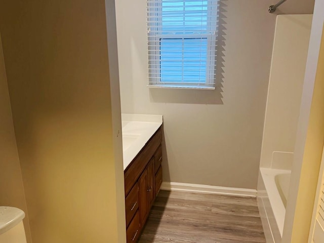 bathroom with vanity, a washtub, toilet, a healthy amount of sunlight, and wood-type flooring