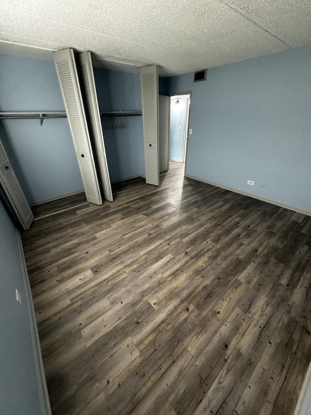 unfurnished bedroom featuring dark hardwood / wood-style flooring and multiple closets