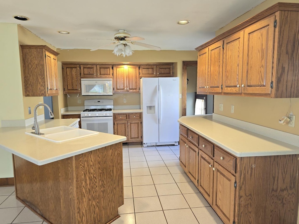 kitchen with kitchen peninsula, white appliances, ceiling fan, sink, and light tile patterned floors