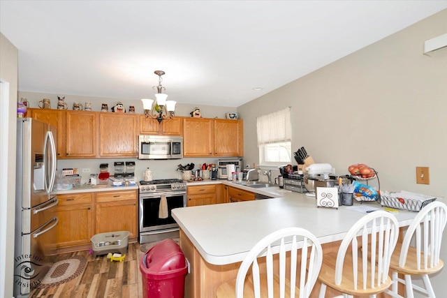 kitchen featuring kitchen peninsula, stainless steel appliances, a notable chandelier, light hardwood / wood-style floors, and hanging light fixtures