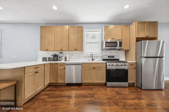 kitchen featuring kitchen peninsula, appliances with stainless steel finishes, dark hardwood / wood-style flooring, sink, and light brown cabinets