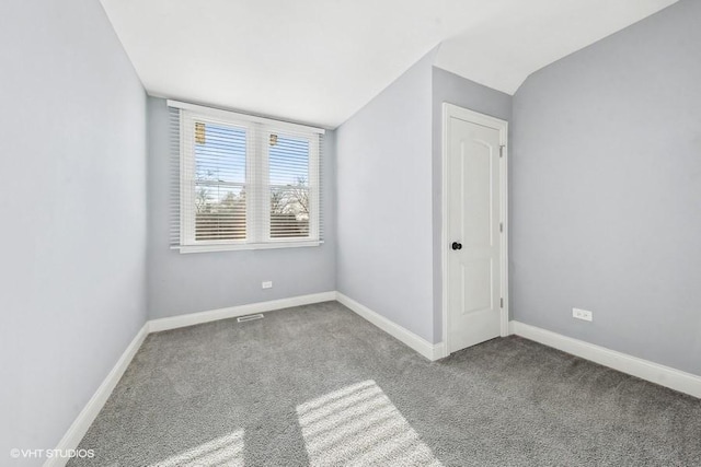 carpeted empty room featuring vaulted ceiling