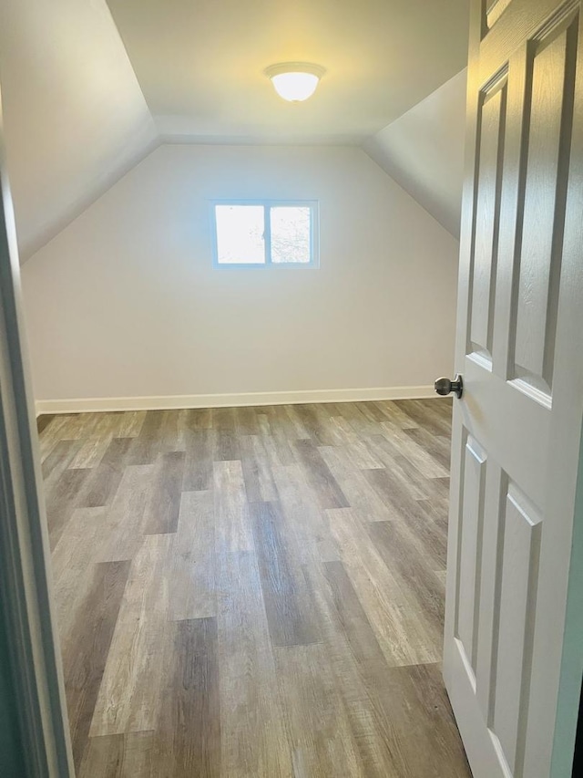 additional living space with light hardwood / wood-style flooring and lofted ceiling