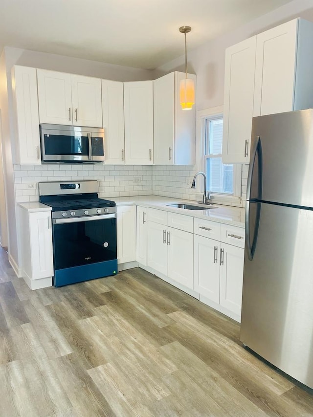 kitchen with white cabinets, appliances with stainless steel finishes, light wood-type flooring, and sink