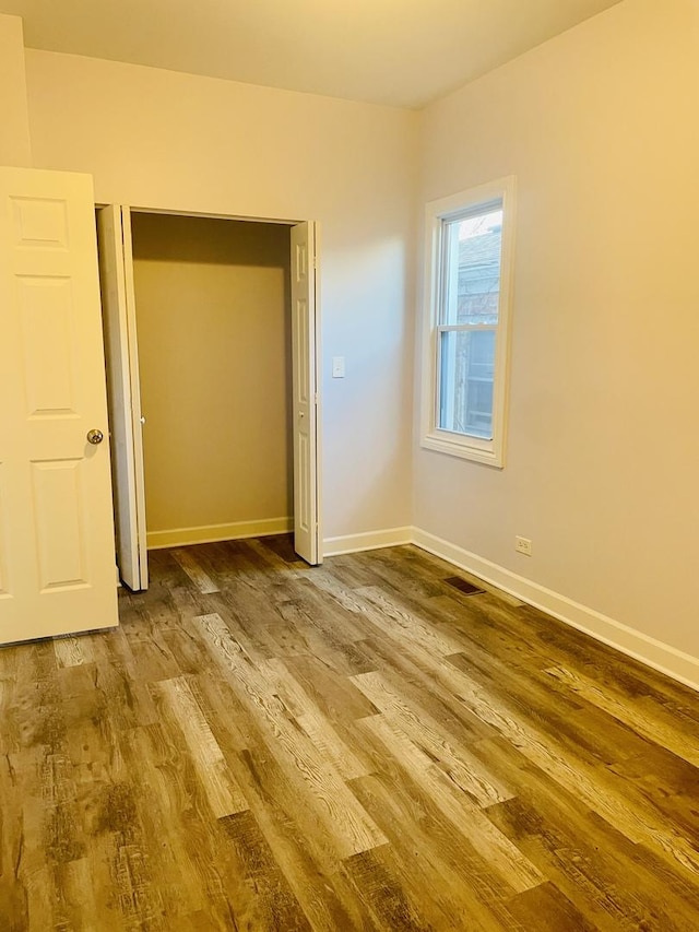 unfurnished bedroom featuring a closet and hardwood / wood-style floors