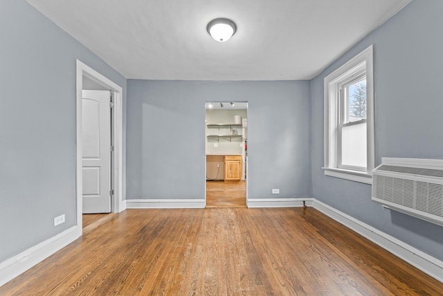 unfurnished room with a wall mounted AC and light hardwood / wood-style floors