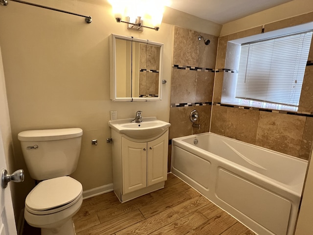 full bathroom with tiled shower / bath, vanity, wood-type flooring, and toilet