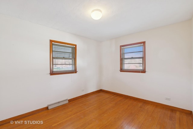 unfurnished room with hardwood / wood-style floors and a baseboard heating unit