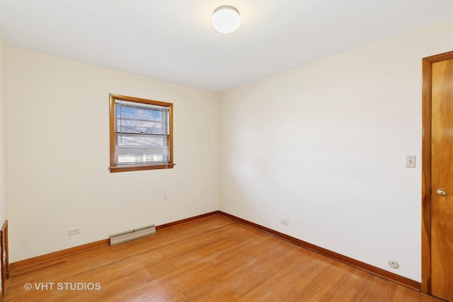 empty room featuring wood-type flooring and a baseboard heating unit