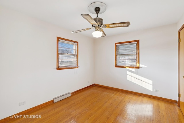 spare room with hardwood / wood-style floors, baseboard heating, and ceiling fan